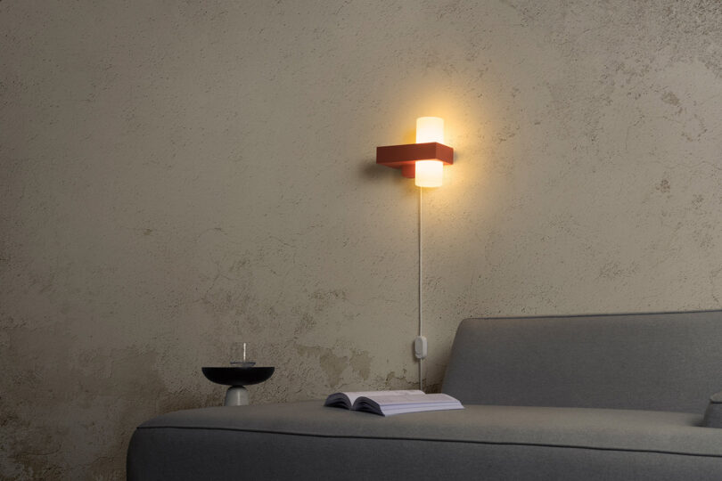 Figra wall lamp glowing softly over a grey sofa.