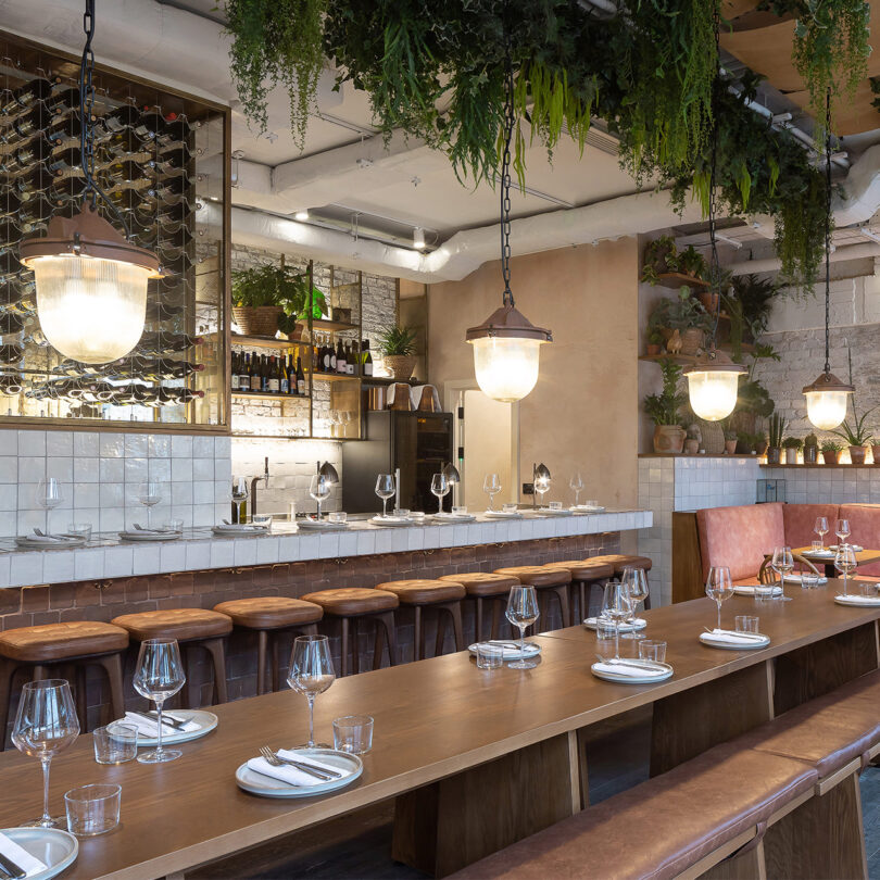 A row of pendant lights hangs above a set table in a restaurant