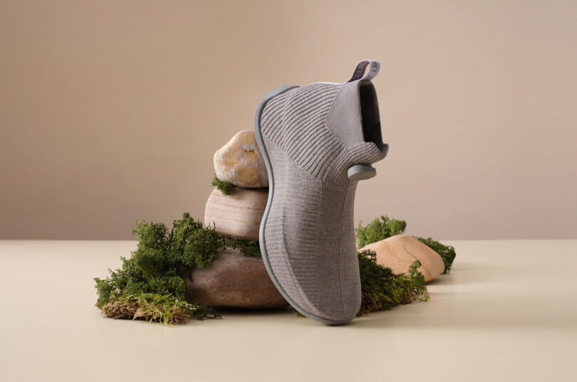 Allbirds' Moonshot merino wool sneaker set angled nearly vertical upon fake moss and stones.