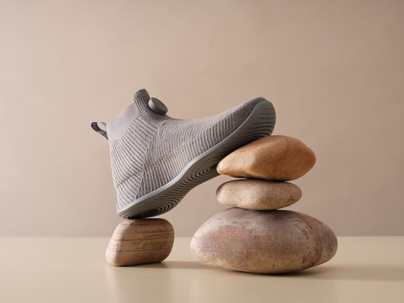 One Allbirds Moonshot sneaker balanced across one stone on the heel and three stones toward the toe of the shoe.