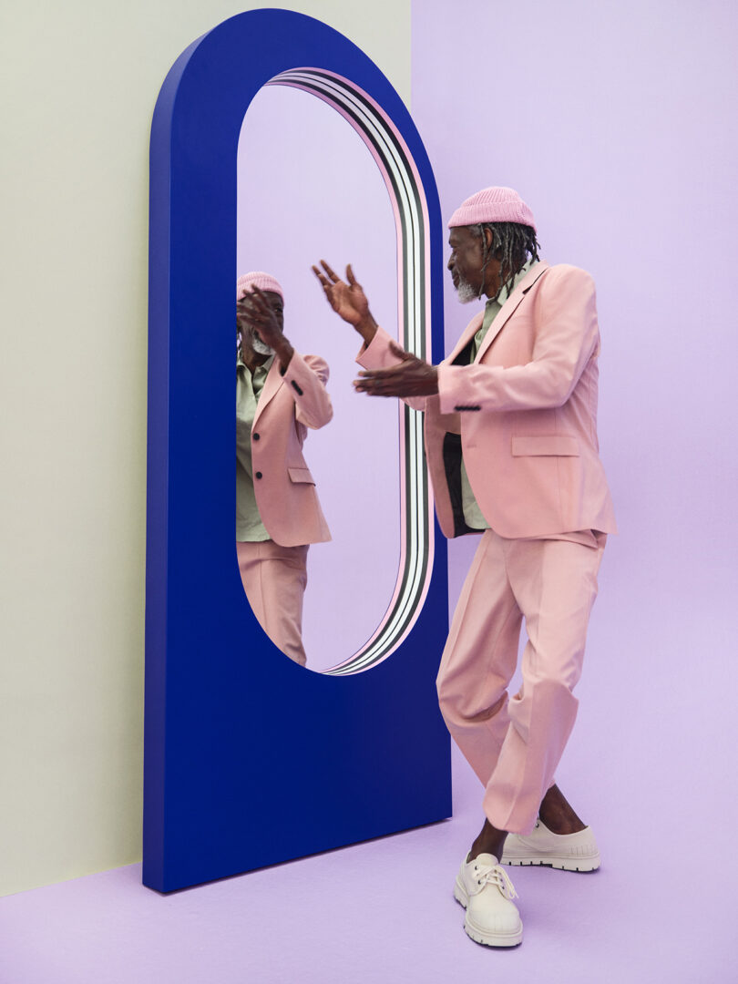 arched cobalt blue floor mirror with brown-skinned man in pink suit