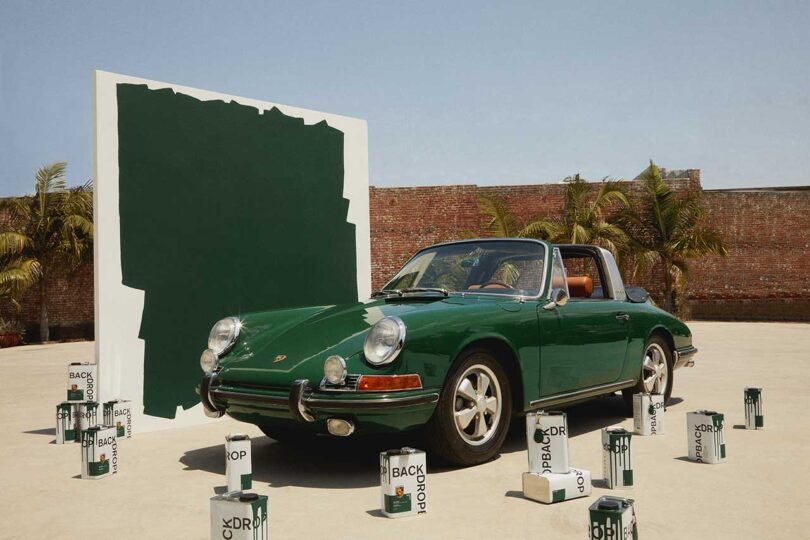 angled view of deep green colored vintage Porsche with matching large paint swatch in back and cans of green paint in front