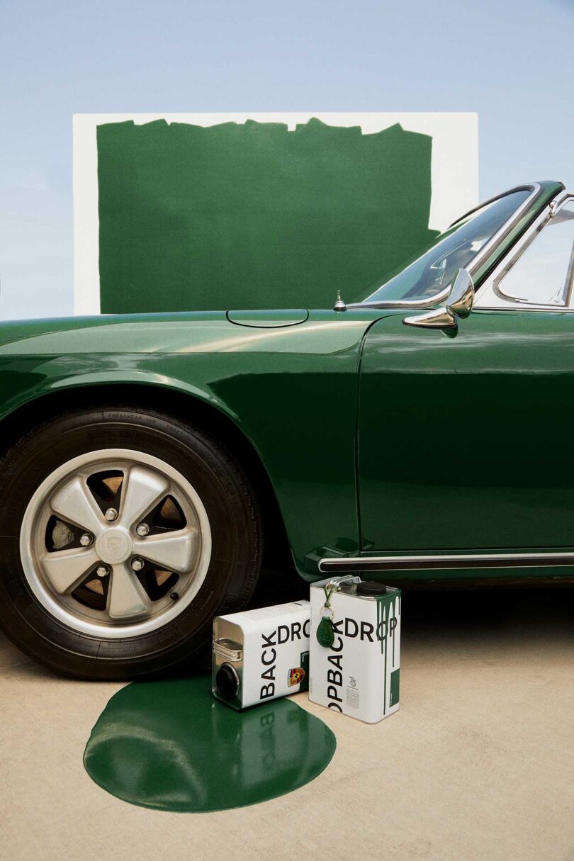 close up partial view of vintage Porsche painted a deep green with cans of paint spilled in front