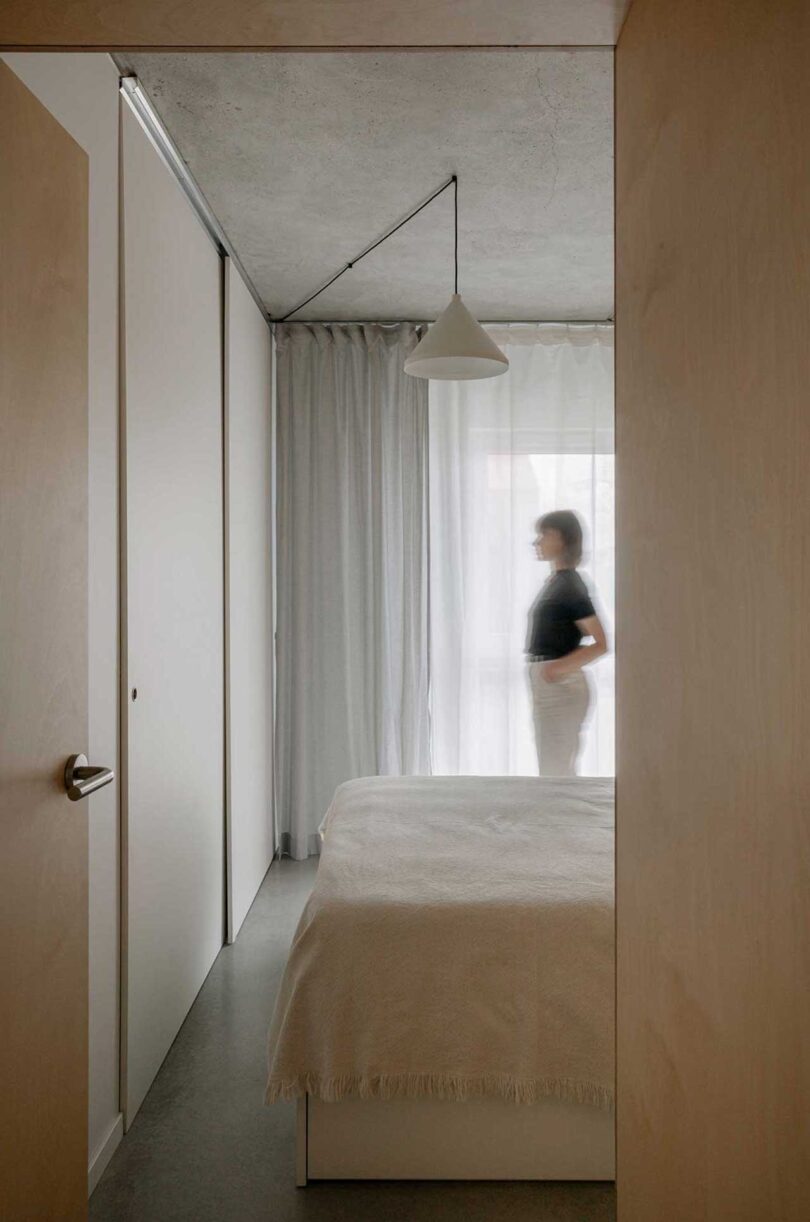 view in hallway looking into wood box structure housing minimalist bedroom in apartment