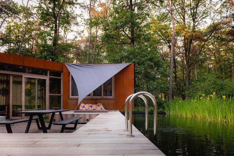 partial exterior view of modern home in the woods with deck and pool