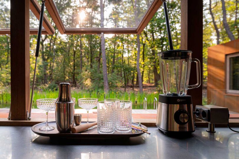 view of countertop bar fixtures looking out through open windows into forest