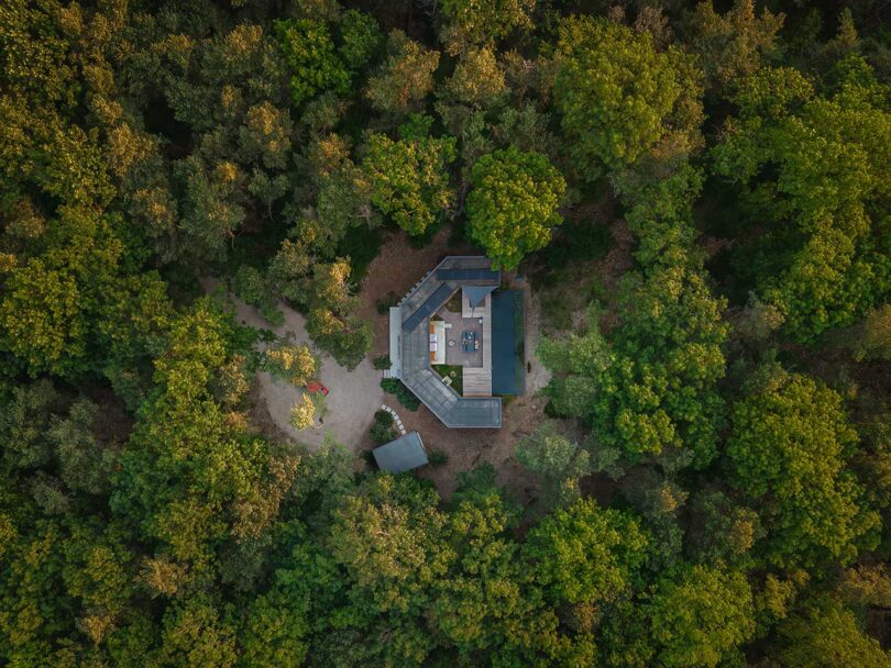 high drone view looking down to c-shaped modern house in the woods