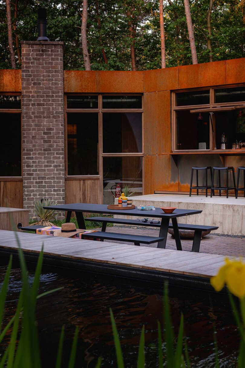 exterior view of modern home with corten steel exterior and picnic table on deck