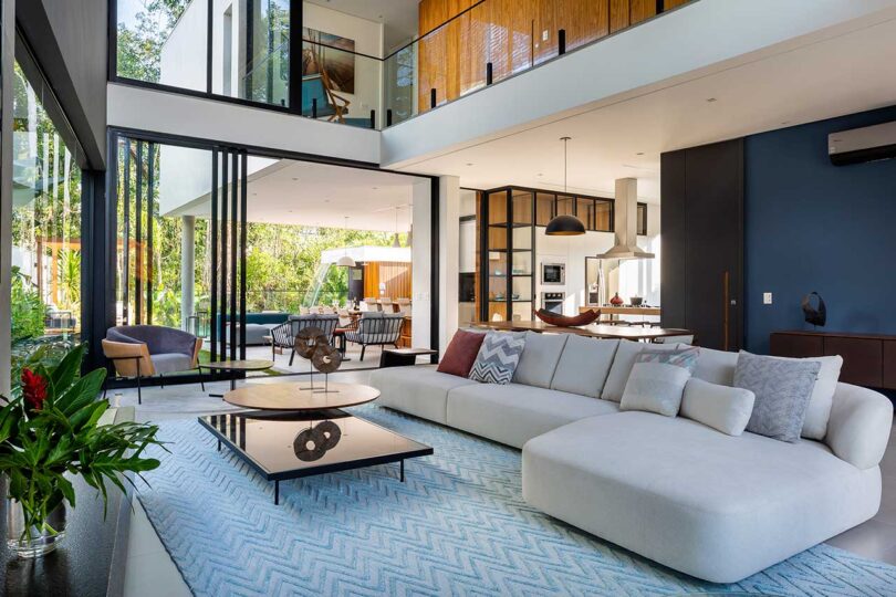 angled interior view of modern double-height living room with views outside and into kitchen