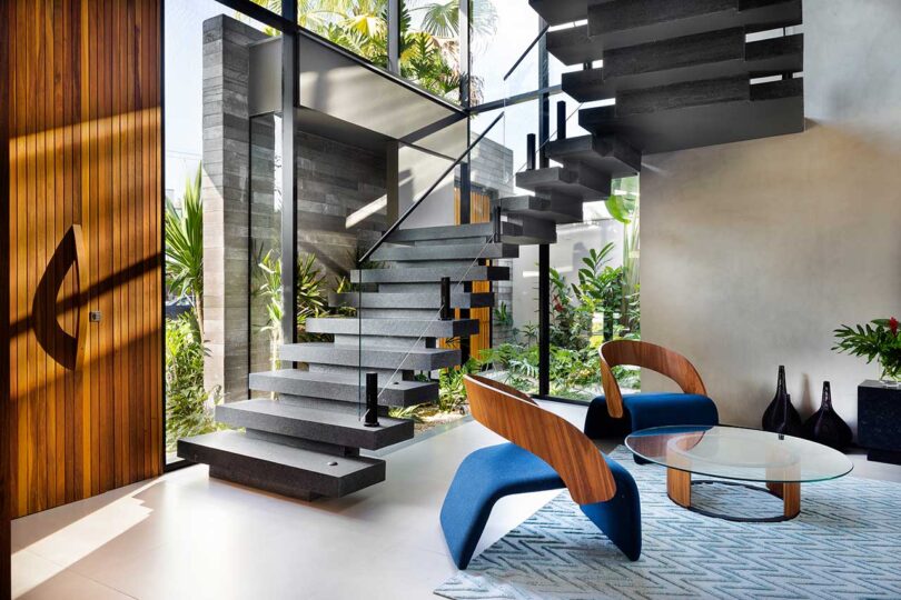 angled view of front entryway in modern home with dramatic open staircase and sitting area