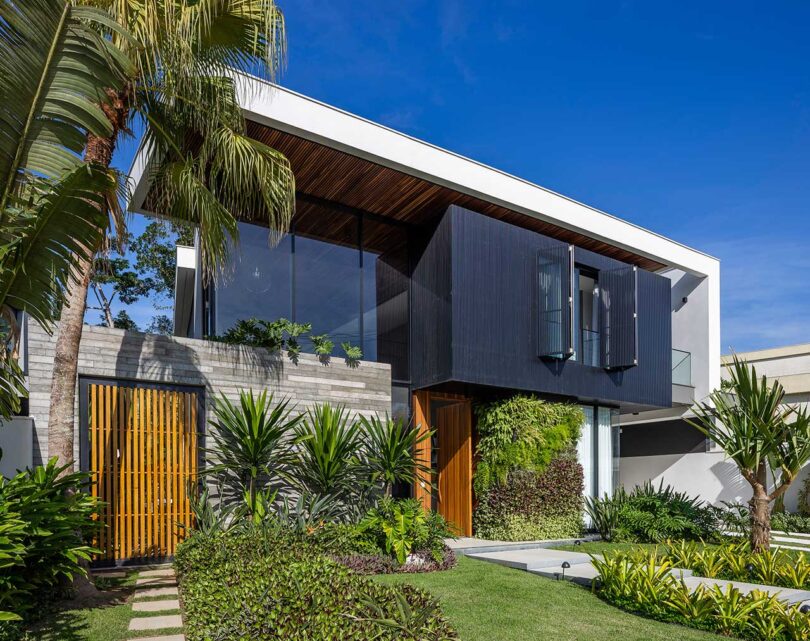 angled front view of modern house exterior with slatted shade on front surrounded by plants