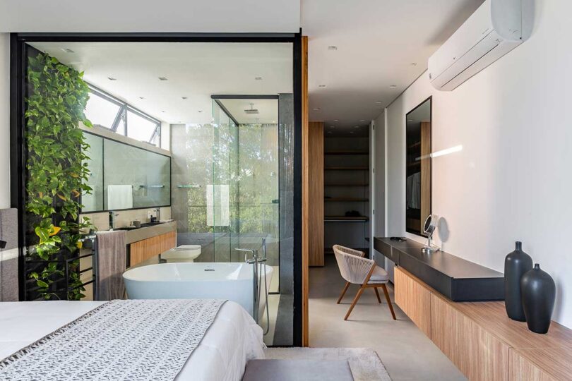 partial view of modern bedroom with glass enclosed bathroom