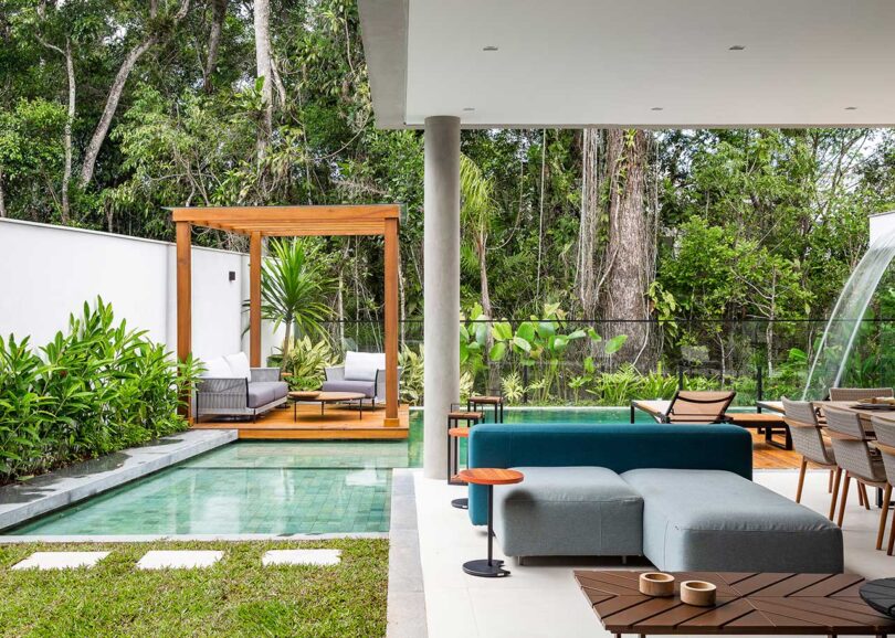 Vista al patio cubierto de una casa moderna con cocina al aire libre, comedor y sala de estar con vista a la piscina