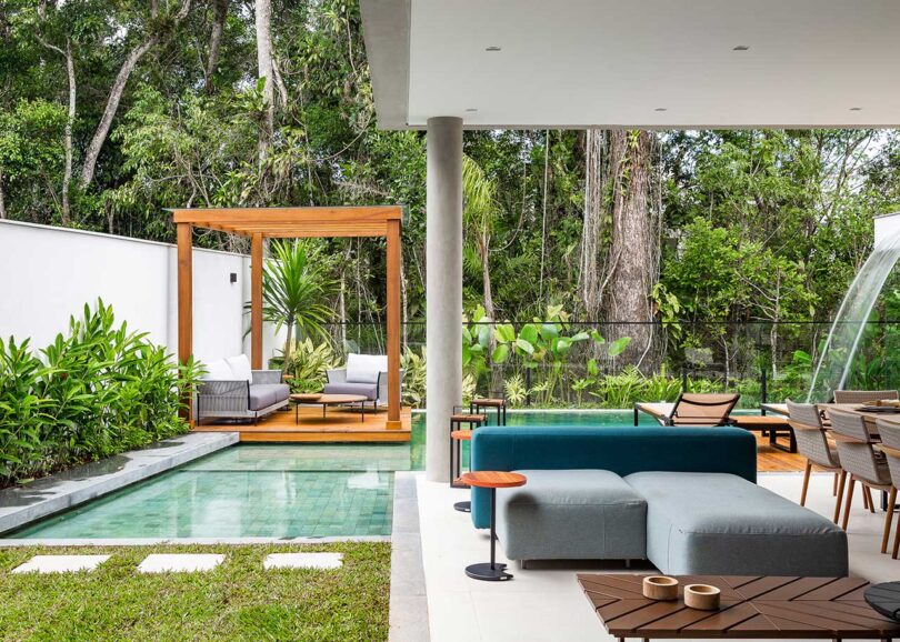 covered patio view of modern house with outdoor kitchen, eating and seating areas with view of pool