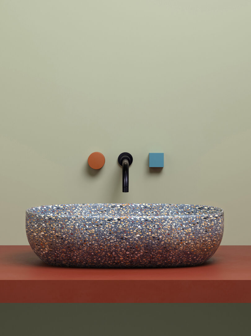 rounded mottled terrazzo sink with burnt orange and sky blue faucet handles