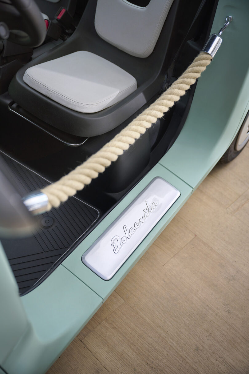 angled down view of open door of mini Fiat car with rope instead of door