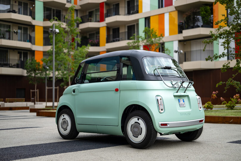 angled partial back view of small mint-colored EV car