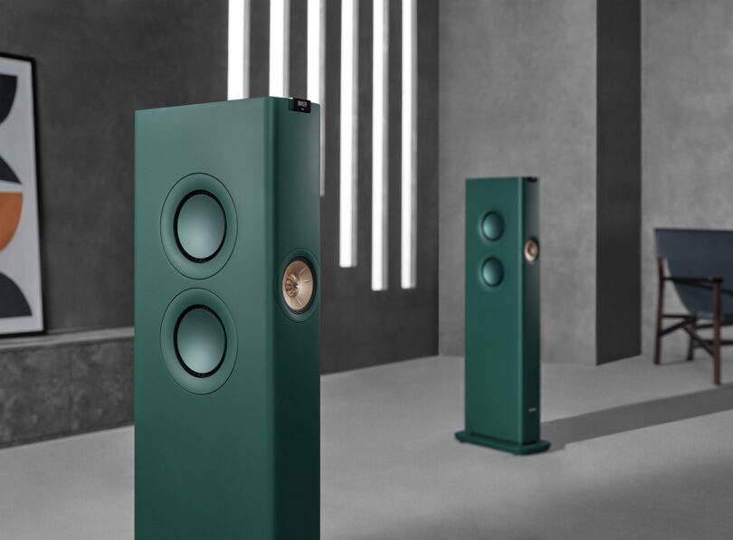 Angled view of KEF LS60 Wireless Lotus Edition Speakers in British Racing Green within modernist concrete wall interior.