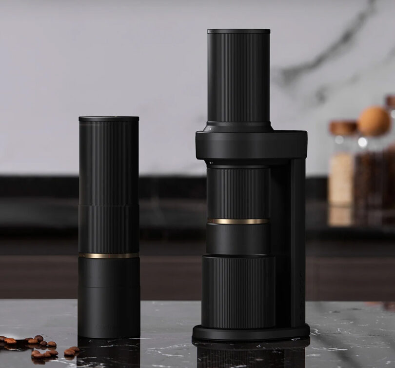 Two Cocinare Essence coffee grinder, one in portable mode, the other attached to the base, set on a black marble countertop. 