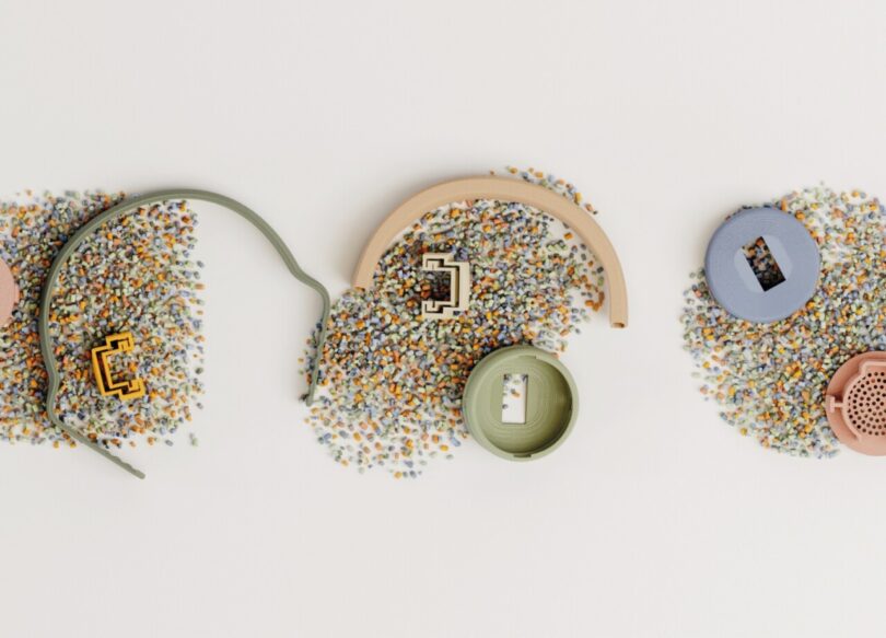 Disassembled Kibu headphone pieces on top of recycled raw multicolored plastic particles.