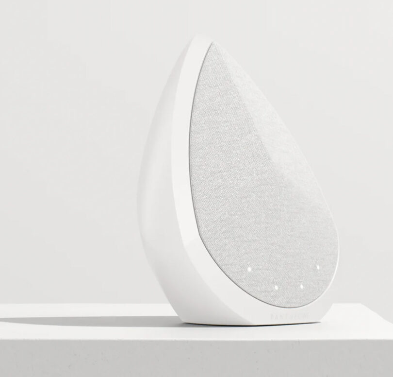 All-white faceted and pointed Pantheone Obsidian wireless speaker set on white surface with white wall background.