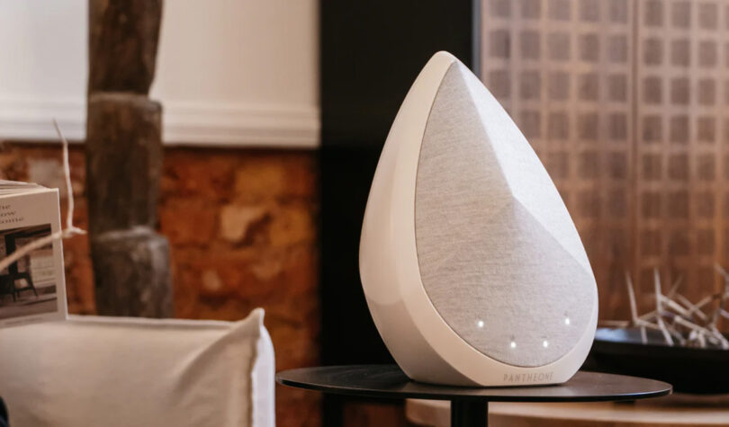Pantheone Obsidian wireless speaker in white set within an organic modern decor setting on black cabinet.
