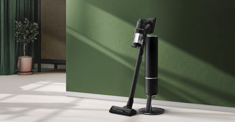Samsung Bespoke AI stick vacuum in matte black set near green painted wall.