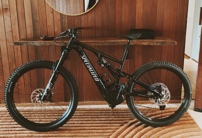 Specialized Levo electric mountain bike leaning against a wood paneled wall.