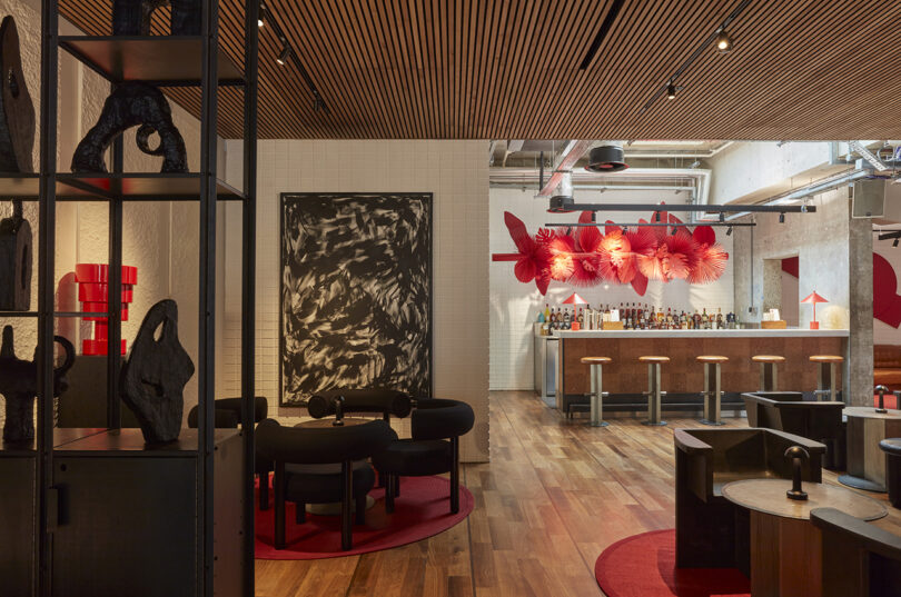 hotel lobby bar with red statement lighting, large wall art, and various seating areas
