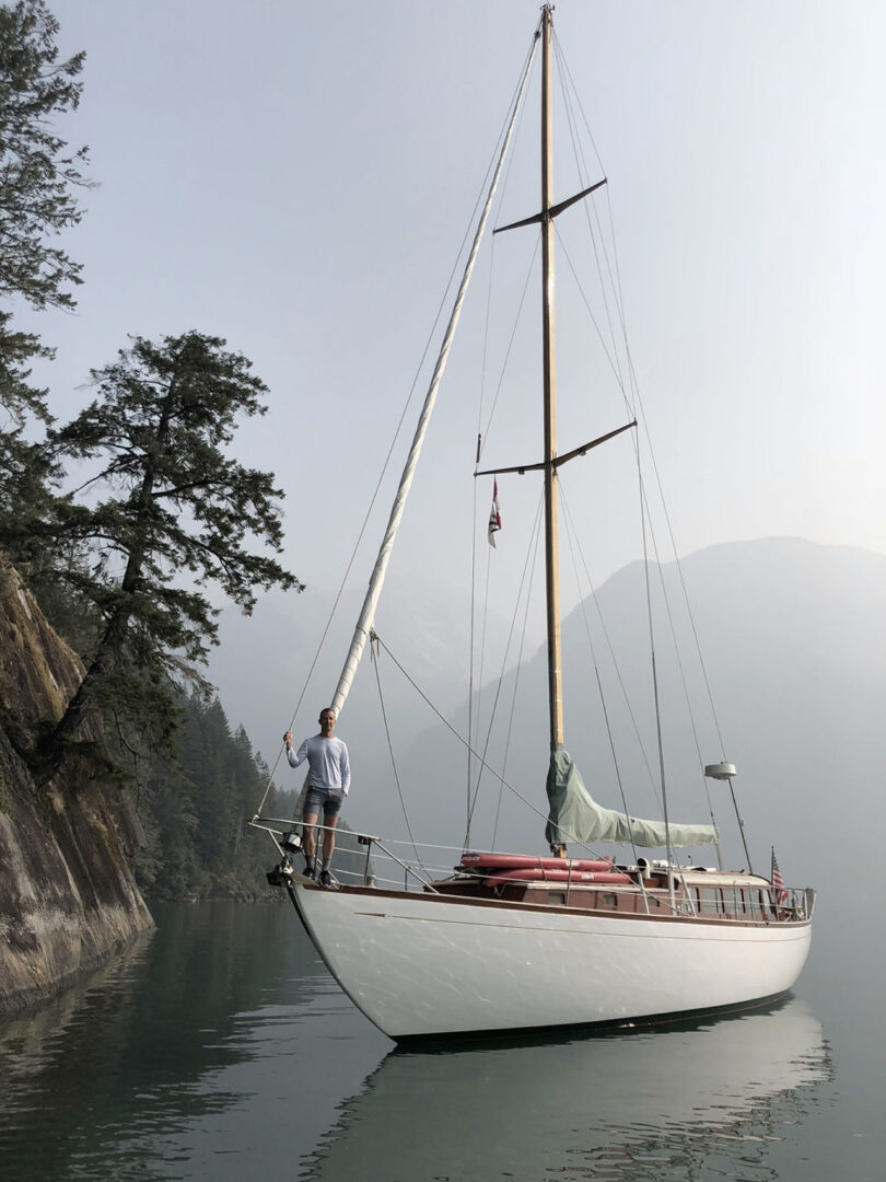 white and wood sailboat anchored in misty waters