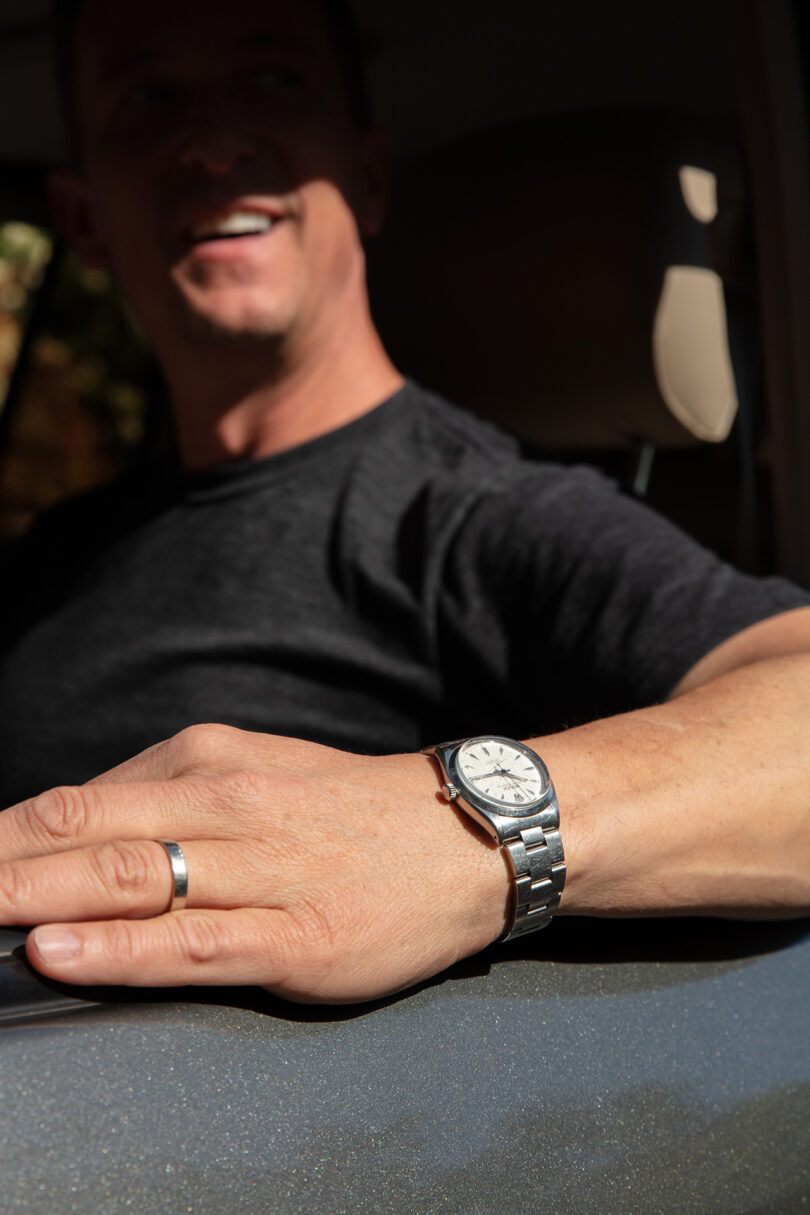 light-skinned man wearing a silver watch and wedding ring