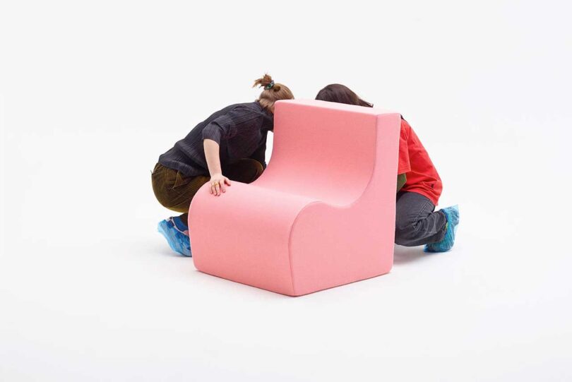 light pink chair being examined by two people on a white background