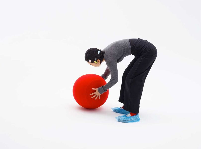 large red ball being examined by a person on a white background