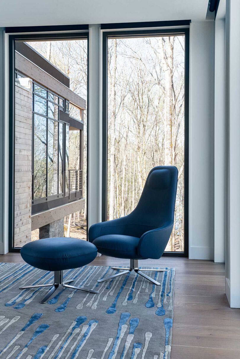 modern blue chair with ottoman in the corner of a room in modern home with floor to ceiling windows