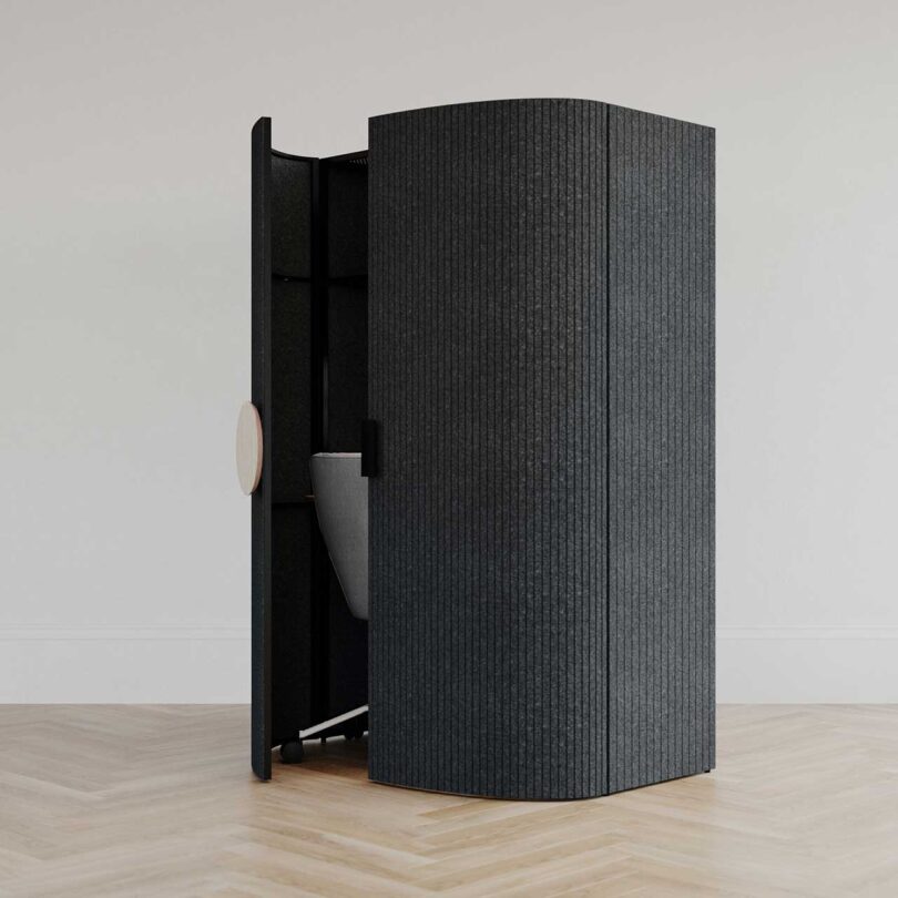 angled view of black rounded front cabinet with doors slightly open revealing a desk chair