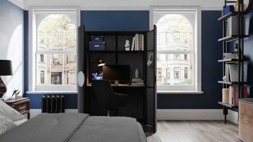 modern bedroom with dark blue walls with black cabinet open housing a work from home desk setup