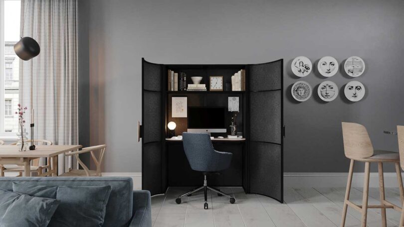 modern living space with black cabinet opened to reveal a work from home office desk setup