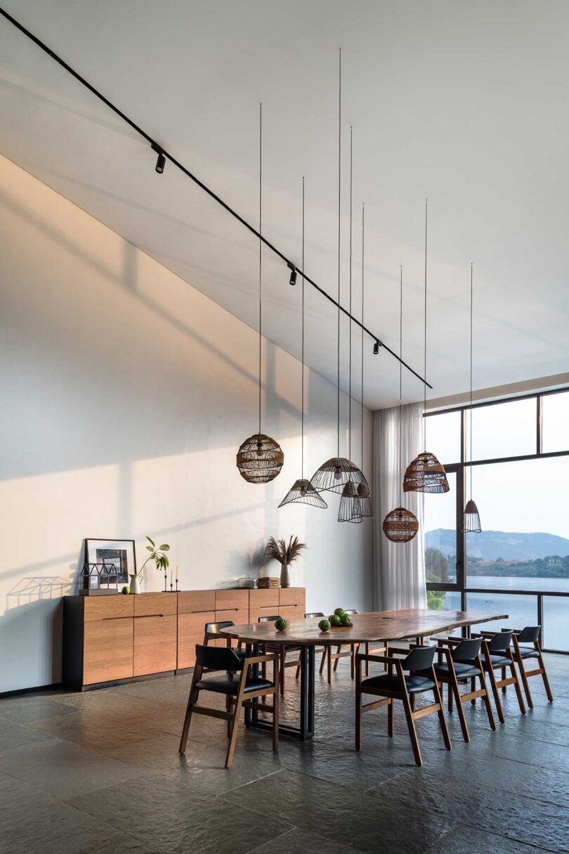 angled view into large open modern dining room with slanted ceilings and window wall looking to lake