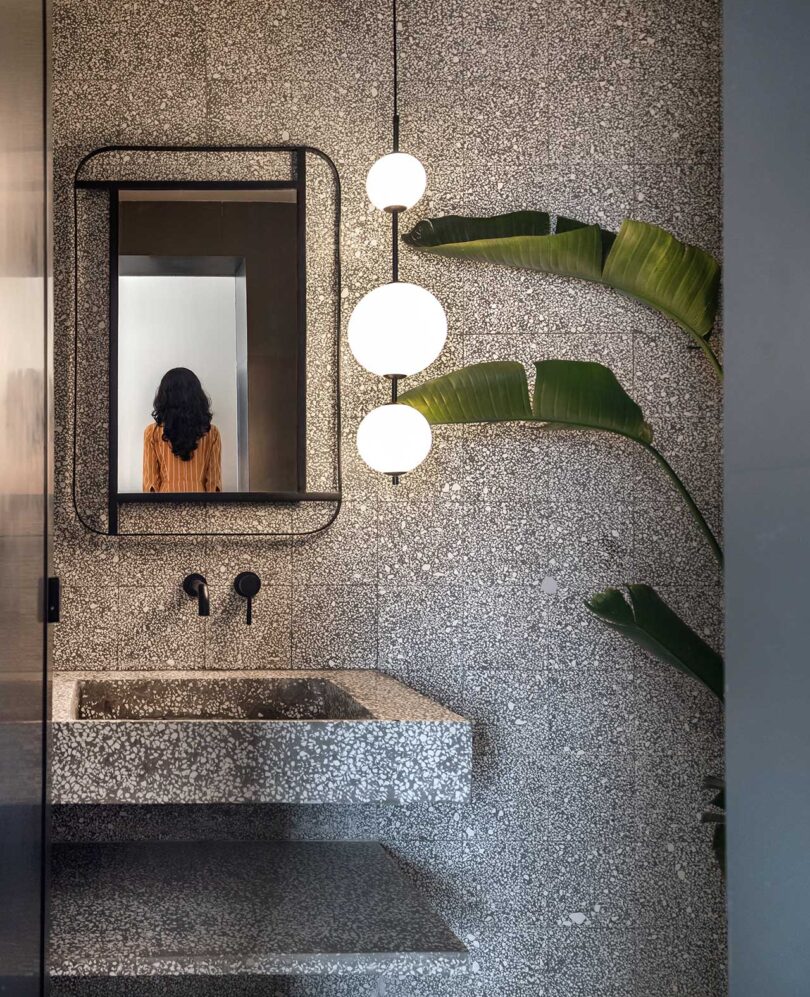 partial view into modern powder bathroom with stone wall and sink