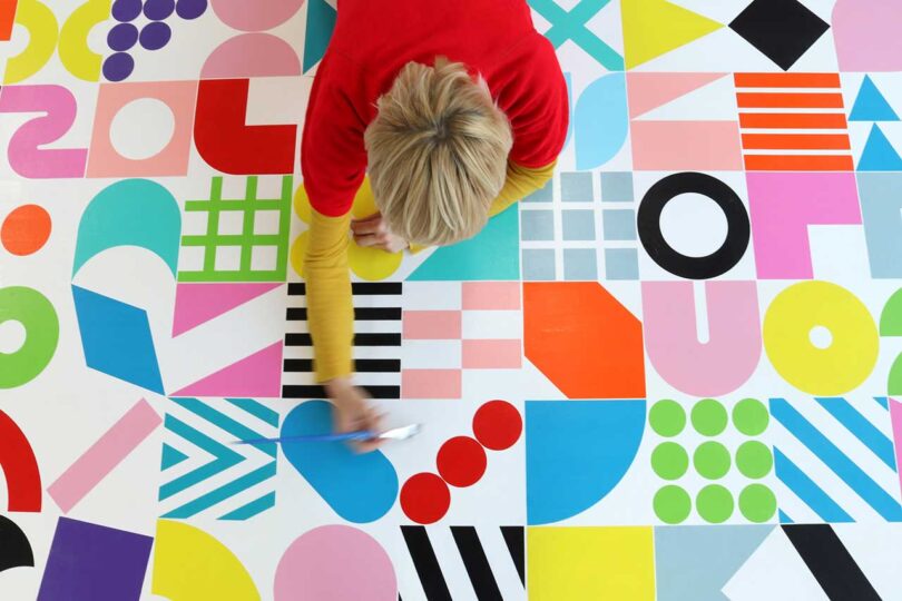 overhead image of a person working on a colorful geometric painting