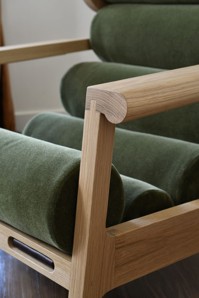 detail of light wood and dark green upholstered armchair