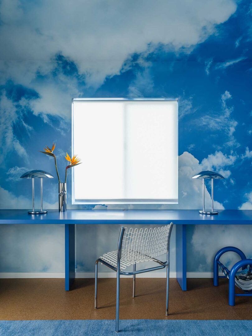 interior shot of home office with long blue modern desk and cloud mural on wall