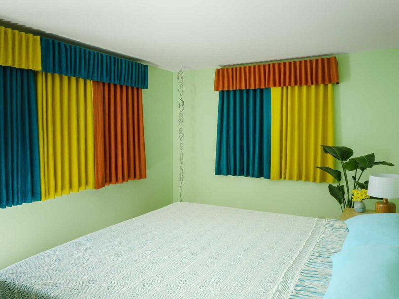angled view of modern bedroom with pale green walls and multicolored curtains