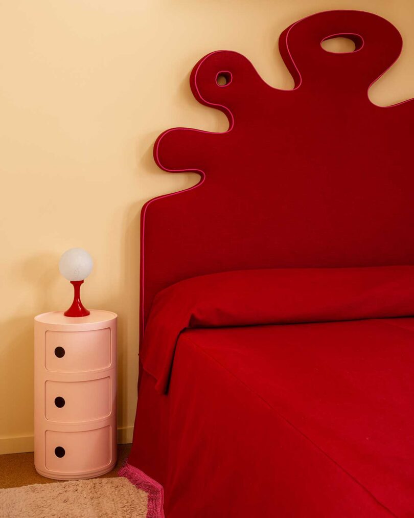 modern bedroom with rusty red organic shaped headboard and bedding with cream colored walls