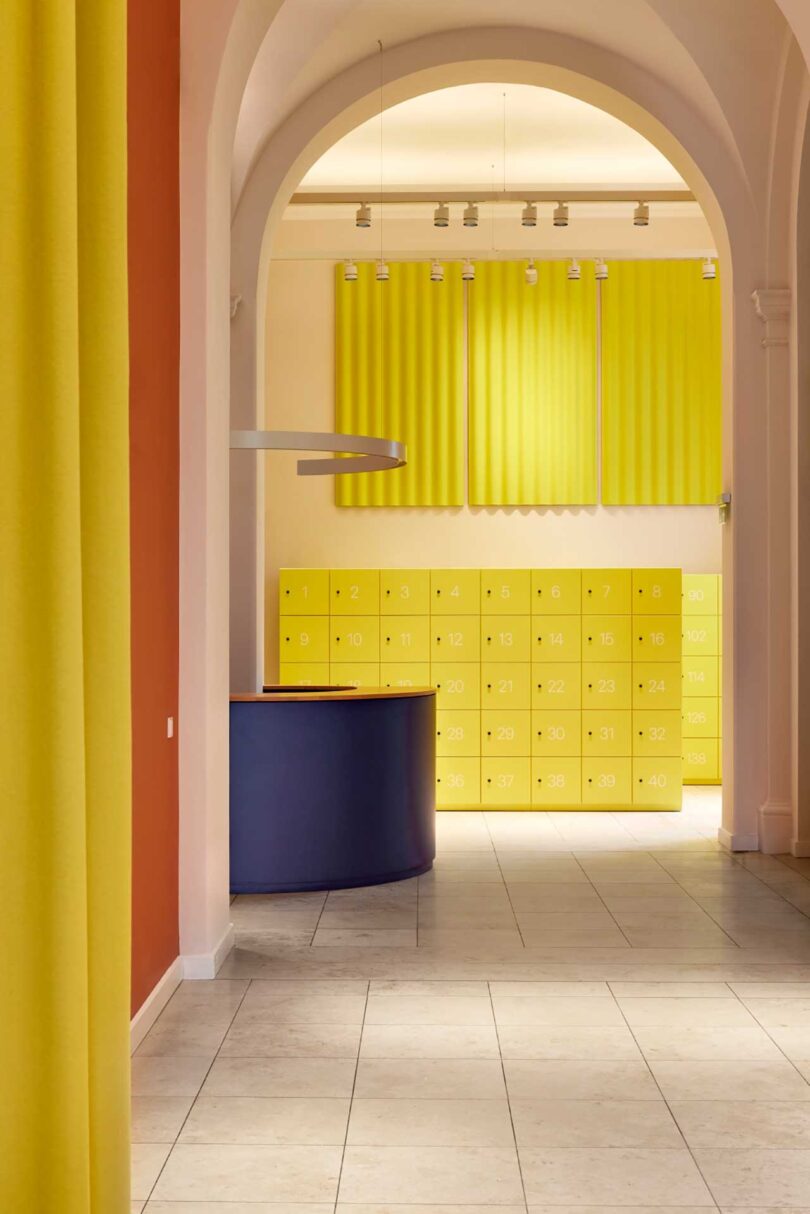 partial interior view of modern museum interior with yellow lockers and blue kiosk