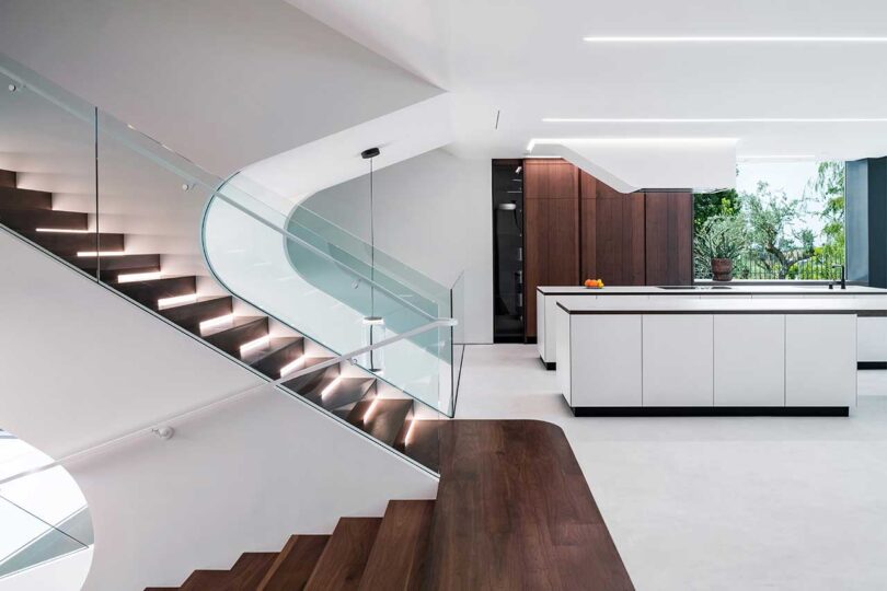 partial interior view of modern futuristic house with view of split staircase and kitchen in back