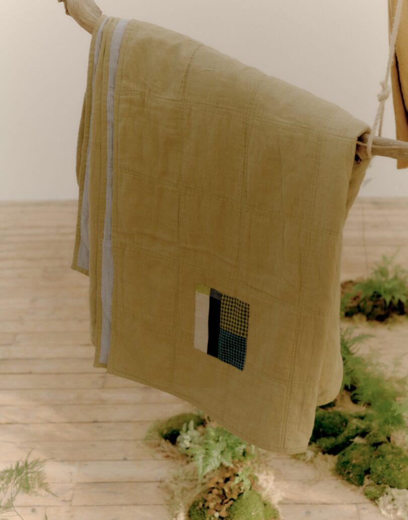 angled view of worn blanket hanging on stick with patched section
