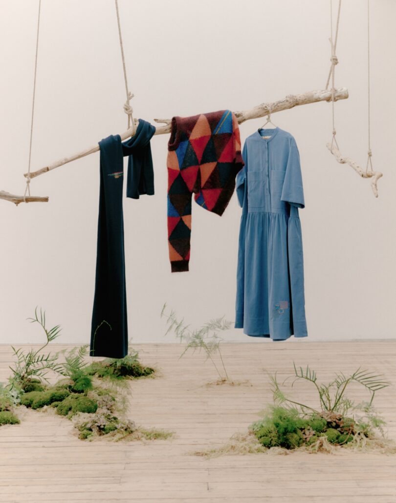 hanging branch holding a denim dress, sweater and scarf
