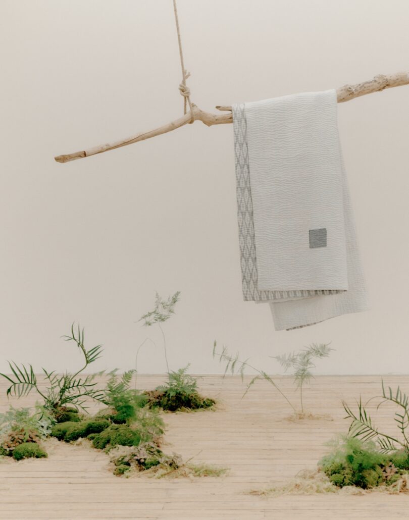 white and patterned grey blanket thrown over suspended branch