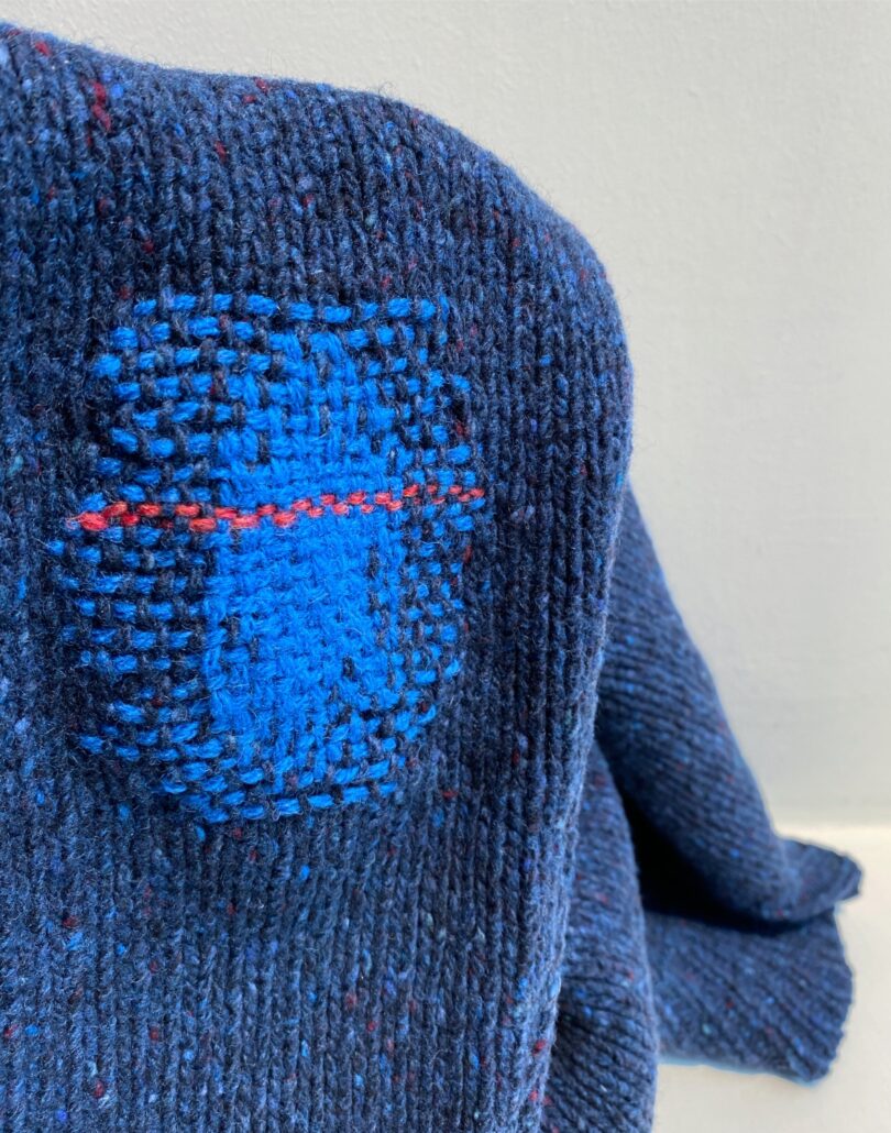 closeup of blue sweater with lighter blue threaded pattern